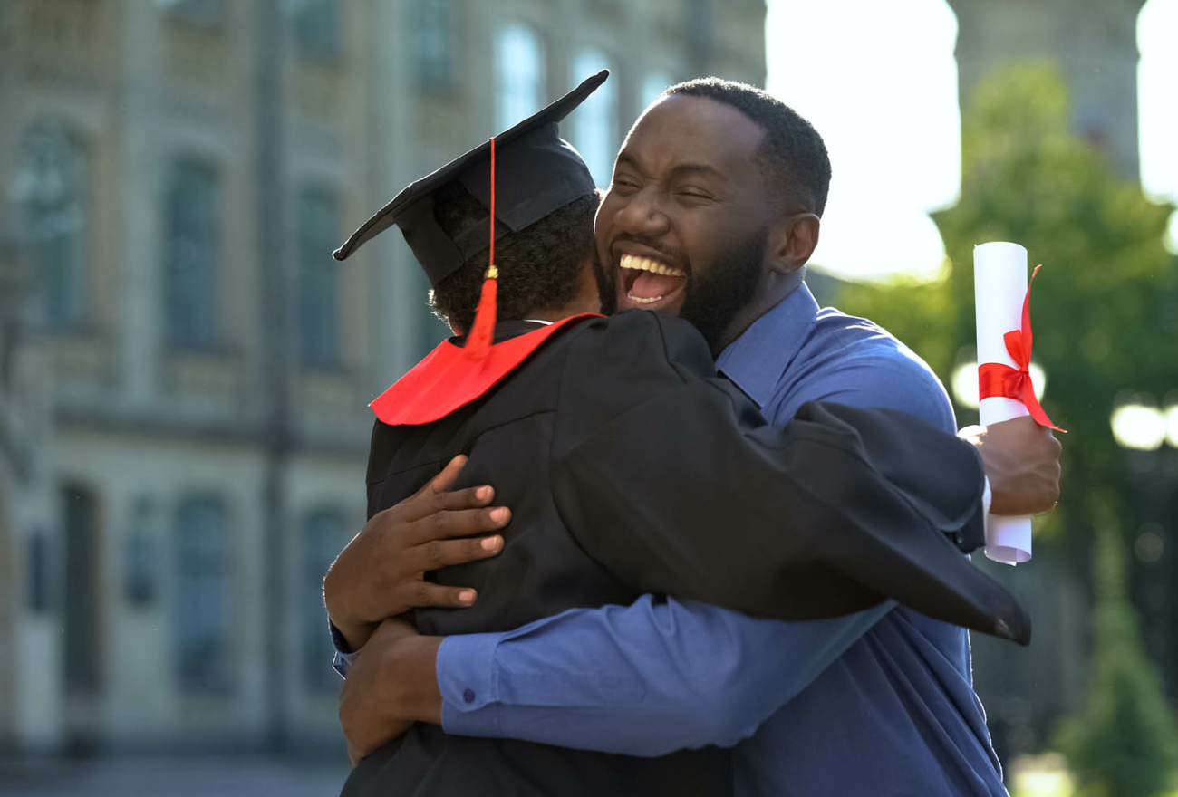 Cheerful father and graduating son hugging outdoor