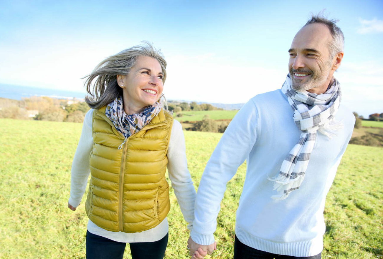 Cheerful senior couple running in countryside